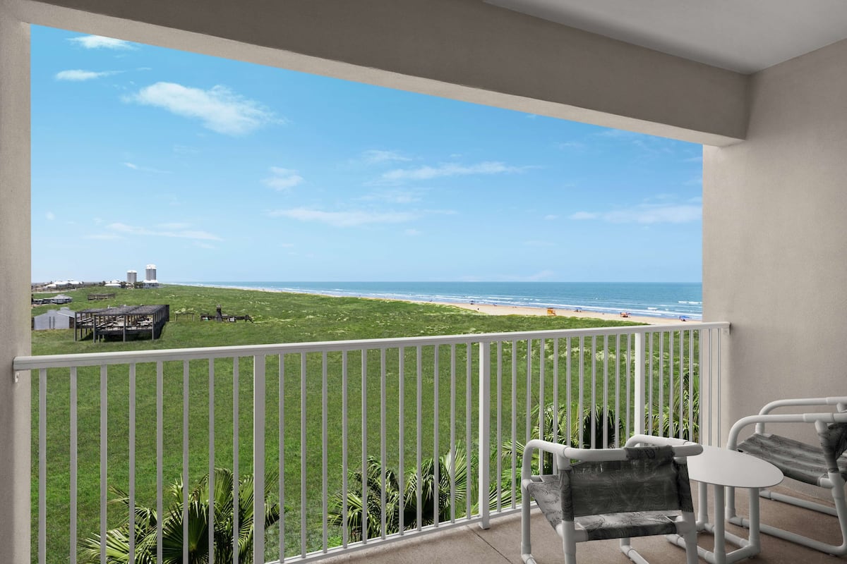 A balcony with a view of the beach and ocean.