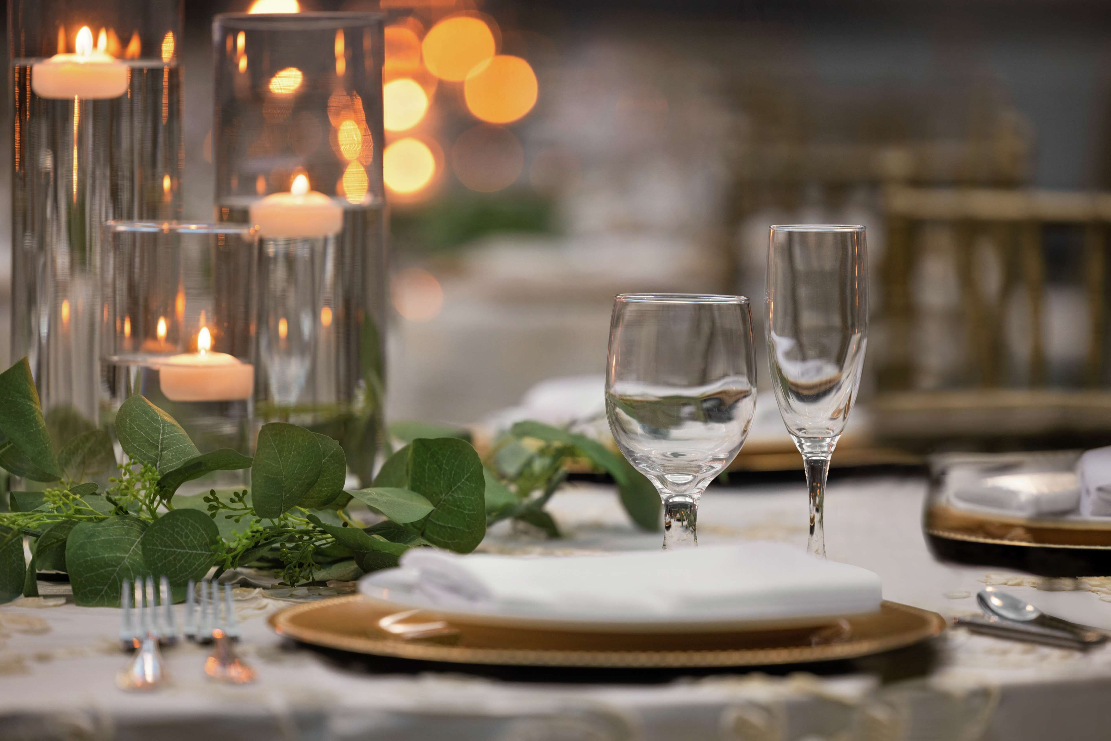 Una mesa dispuesta con velas, copas y un mantel blanco.