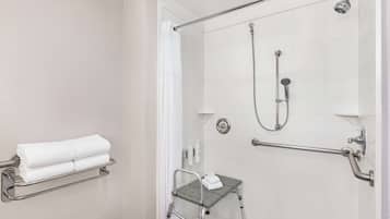Een moderne badkamer met een douche zonder drempel, handgrepen, een klein opstapkrukje en een handdoekhouder.