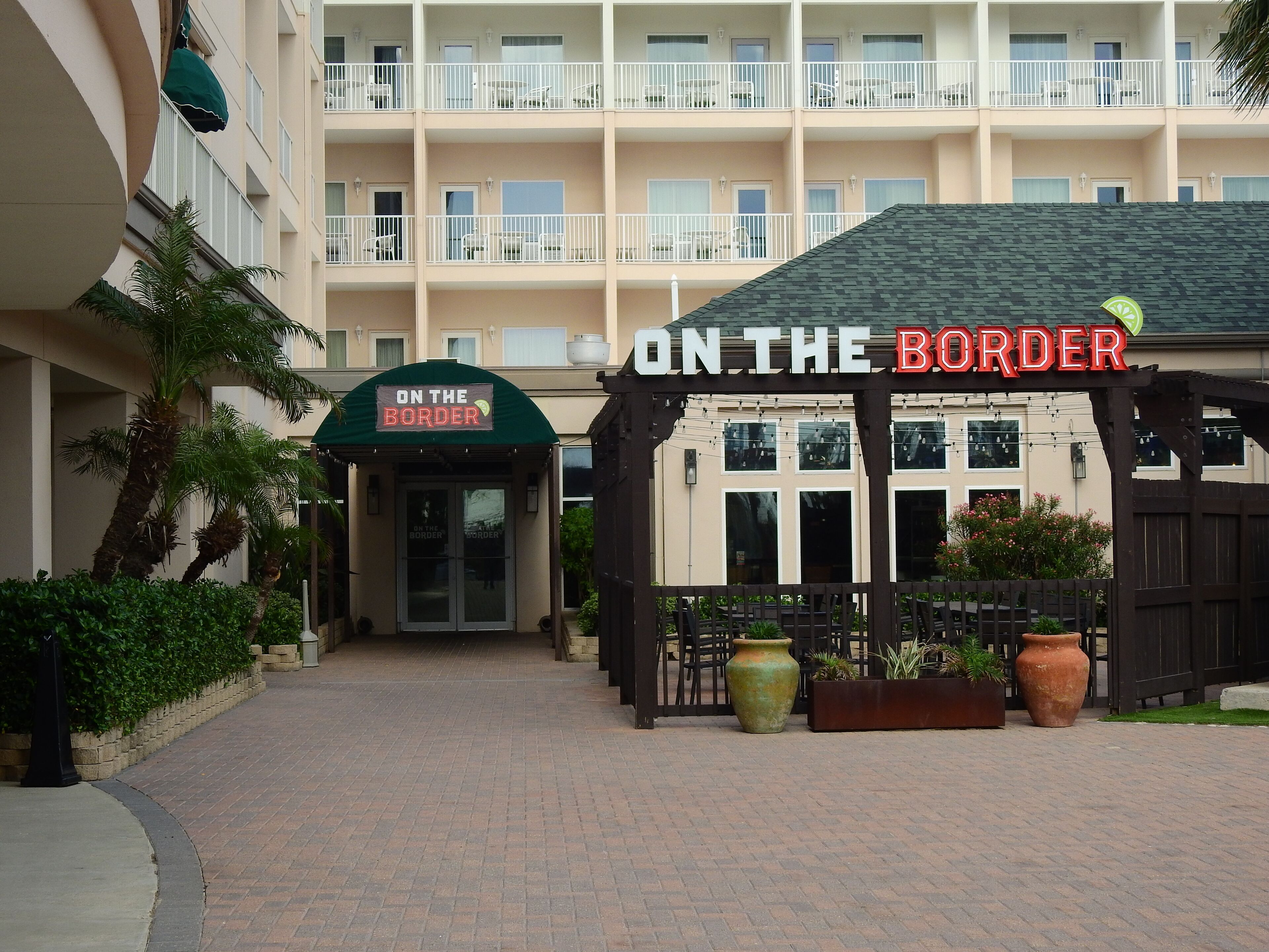 A hotel entrance with a sign reading "ON THE BORDER" and a covered outdoor seating area.