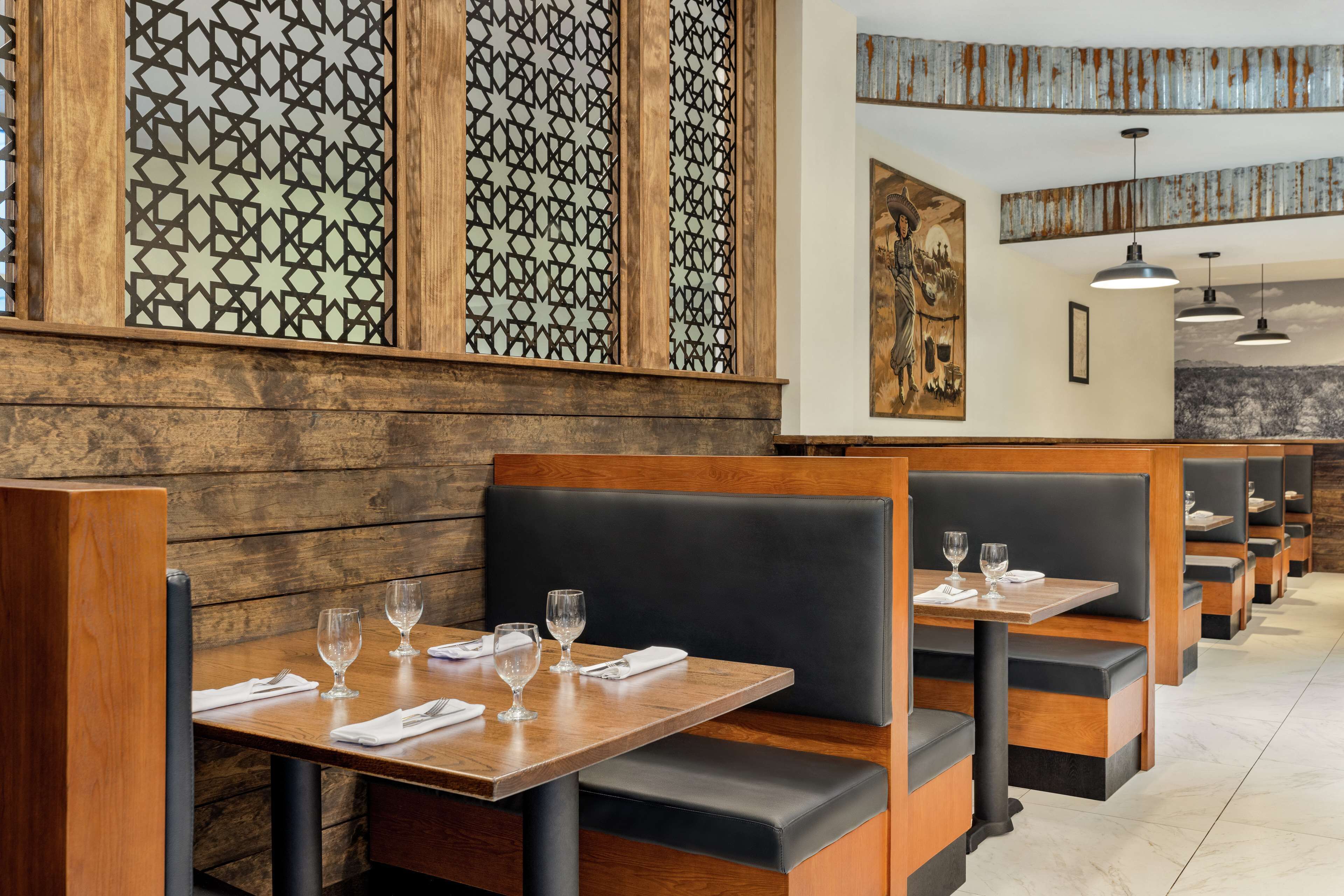 A restaurant with wooden paneling, black cushioned booths, and a mural on the wall.
