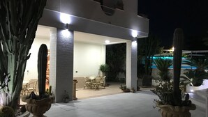 Un espace extérieur aménagé en patio, avec une table et des chaises, entouré de plantes en pot et de cactus.