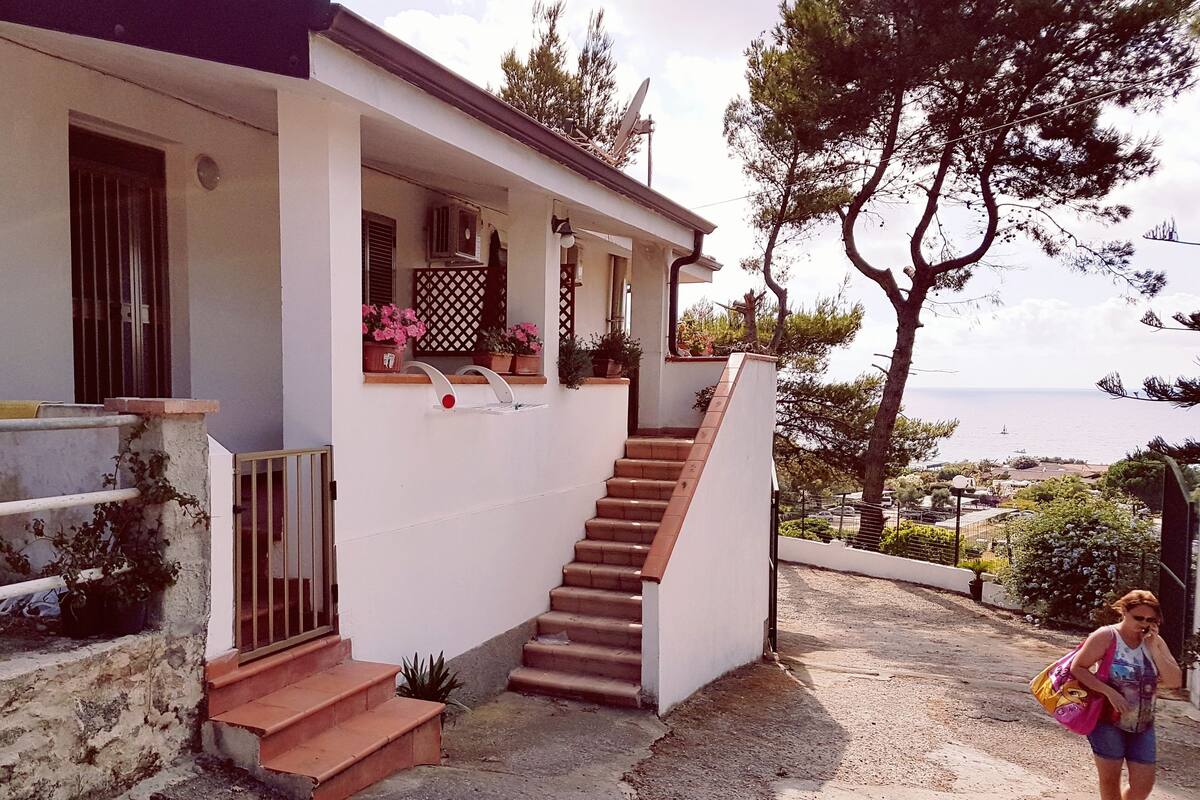 A white building with a staircase leading to a covered porch.