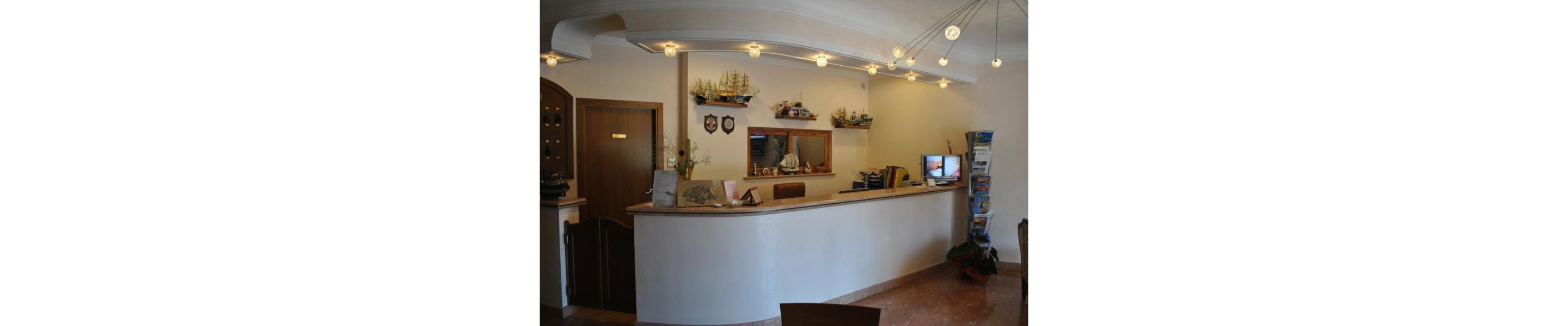 A reception area with a curved counter, a wooden door, and a wall decorated with model ships and a television.