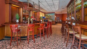 A bar area with wooden bar counters, red chairs, and a patterned carpet. - Chelsea Savoy Hotel (New York)