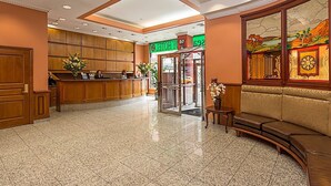 A hotel lobby with a reception desk, a seating area, and a mural on the wall. - Chelsea Savoy Hotel (New York)