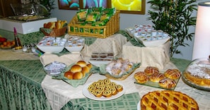 Une table de buffet proposant divers aliments, notamment du pain, des pâtisseries et une tarte.