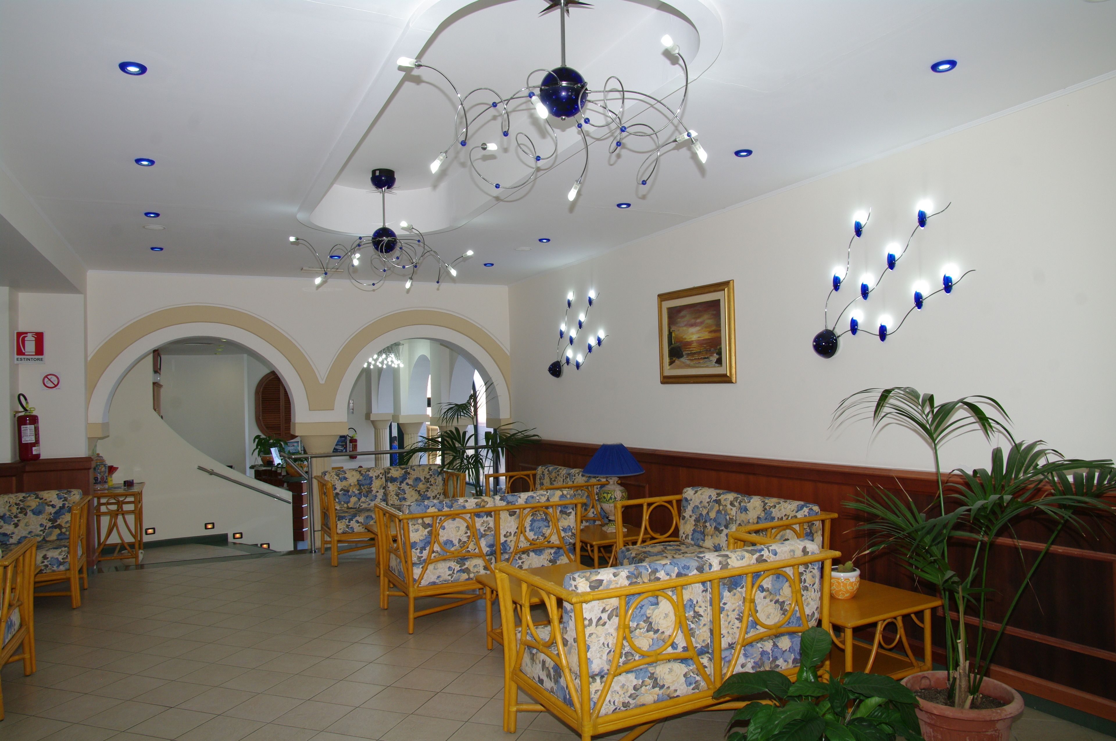 A lobby with wicker furniture, a staircase, and a ceiling light fixture.