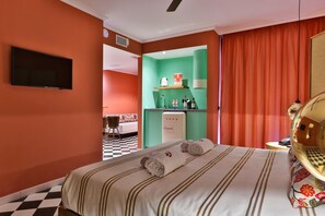 Een hotelkamer met een bed, een televisie, een minibar en een badkamer die door een open deur zichtbaar is.