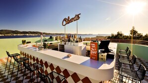 Un espace bar avec vue sur la mer, une enseigne indiquant « Cibano » et un panneau affichant le menu.