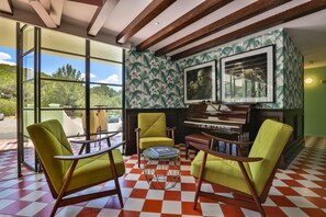A room with large windows, a piano, green chairs, and a checkered floor. - El Coto (Sant Antoni de Portmany)