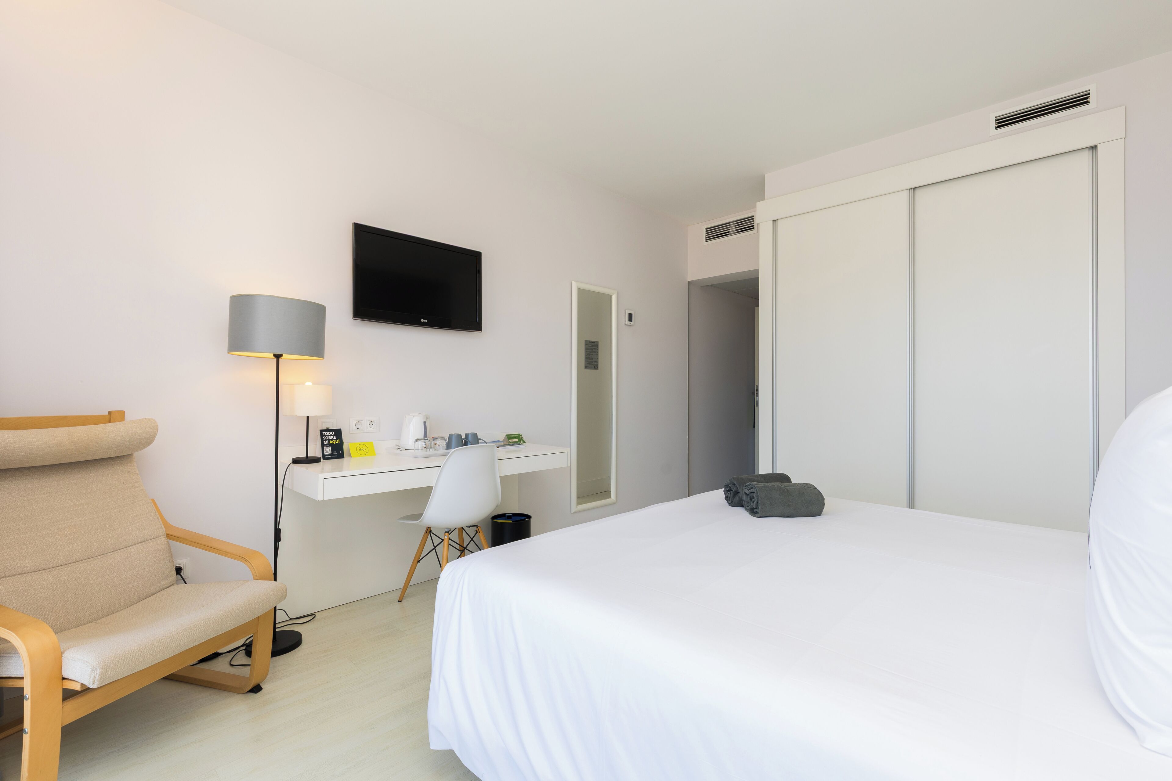 Une chambre d’hôtel équipée d’un lit, d’un bureau, d’une chaise, d’une télévision et d’une armoire.