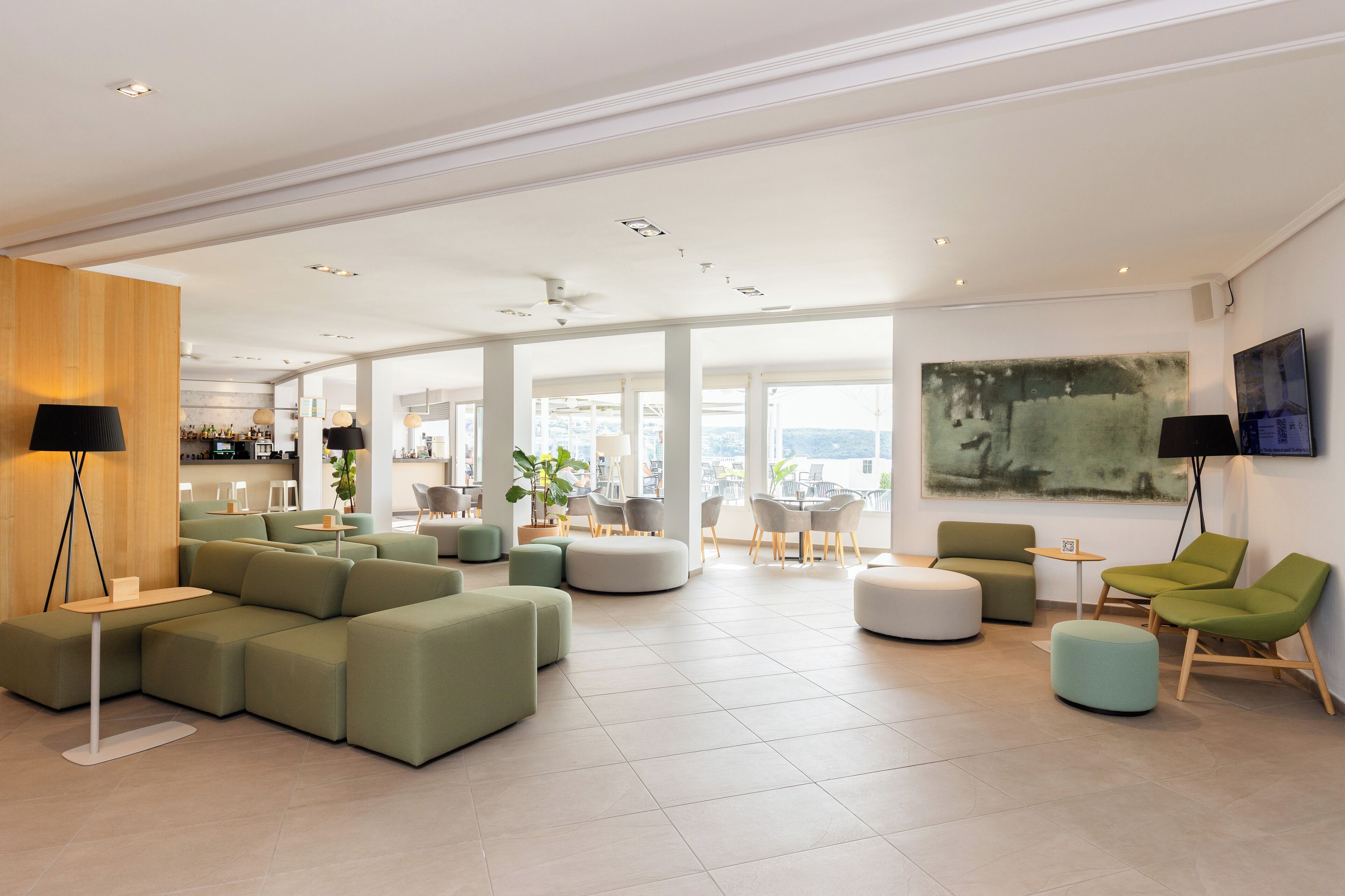 A spacious living area with a sectional sofa, ottomans, and a flat-screen TV mounted on the wall.