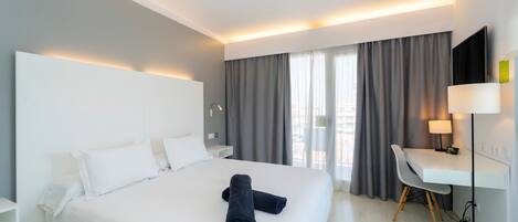 Ein modernes Hotelzimmer mit einem großen Bett, einem Schreibtisch und einem Fernseher.