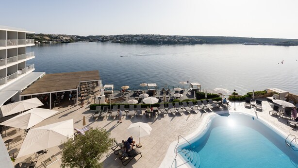 A resort with a swimming pool, lounge chairs, umbrellas, and a view of the water. - ARTIEM Carlos - Adults Only Hotel (Es Castell)