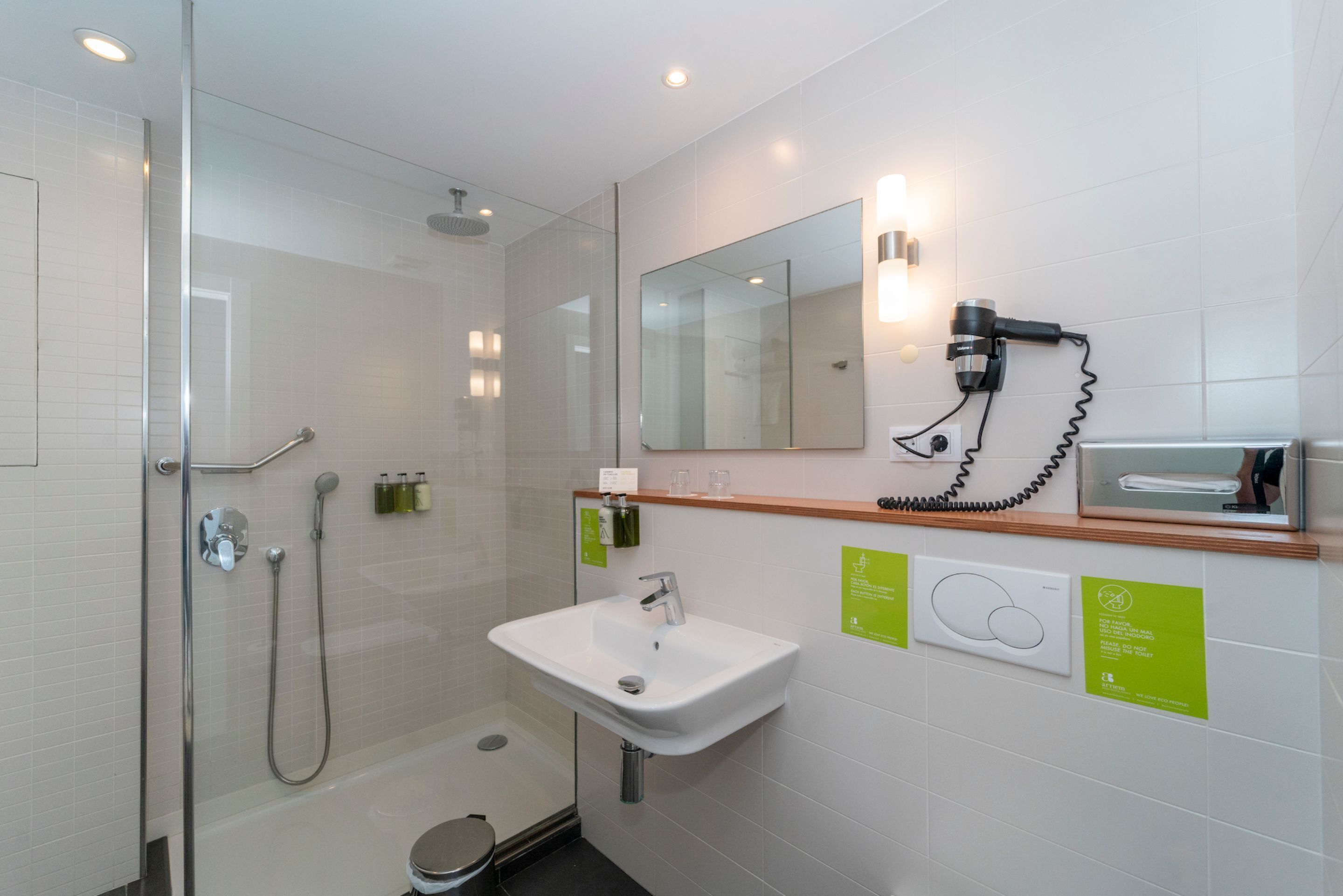 A modern bathroom with a glass shower enclosure, a white sink, and a mirror above it.