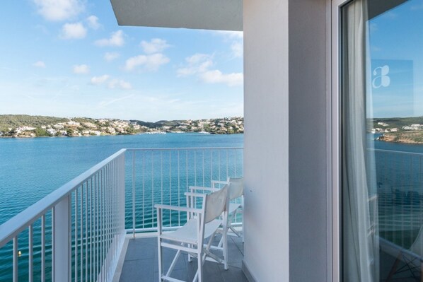 A balcony with a view of a body of water and distant buildings.