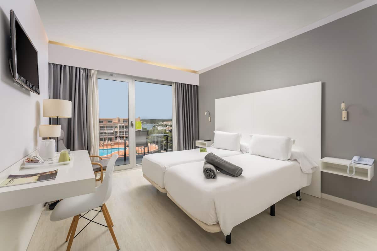 Una habitación de hotel moderna con una cama grande, un escritorio y un televisor.