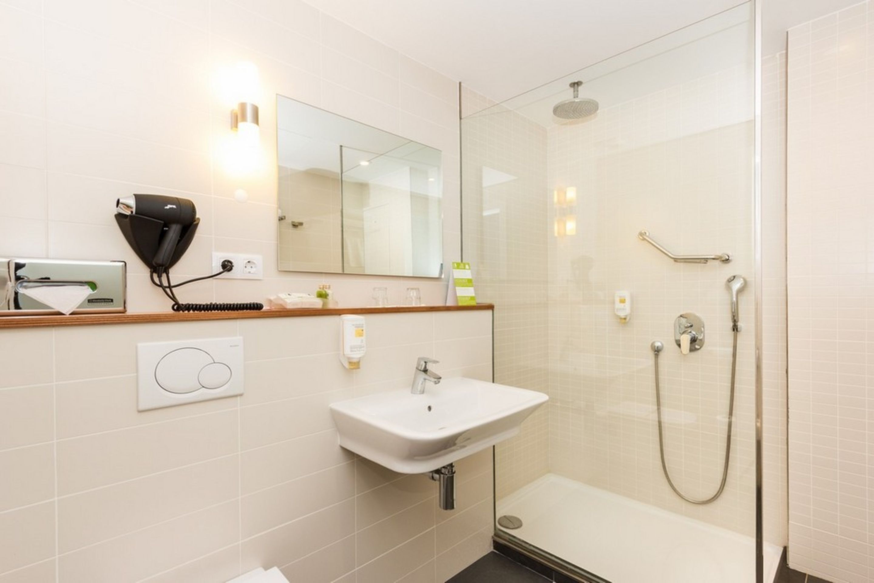 A modern bathroom with a glass-enclosed shower, a white sink, a hairdryer, and a mirror.