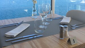 A dining table with a number 5 sign, set with cutlery, glasses, and salt shakers, overlooking a marina with boats. - ARTIEM Carlos - Adults Only Hotel (Es Castell)