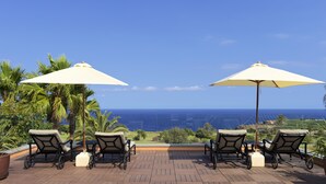 A terrace with two lounge chairs and umbrellas, overlooking a coastal view. - Hotel Hacienda del Conde Meliá Collection Golf & Spa – Adults Only (Buenavista del Norte)