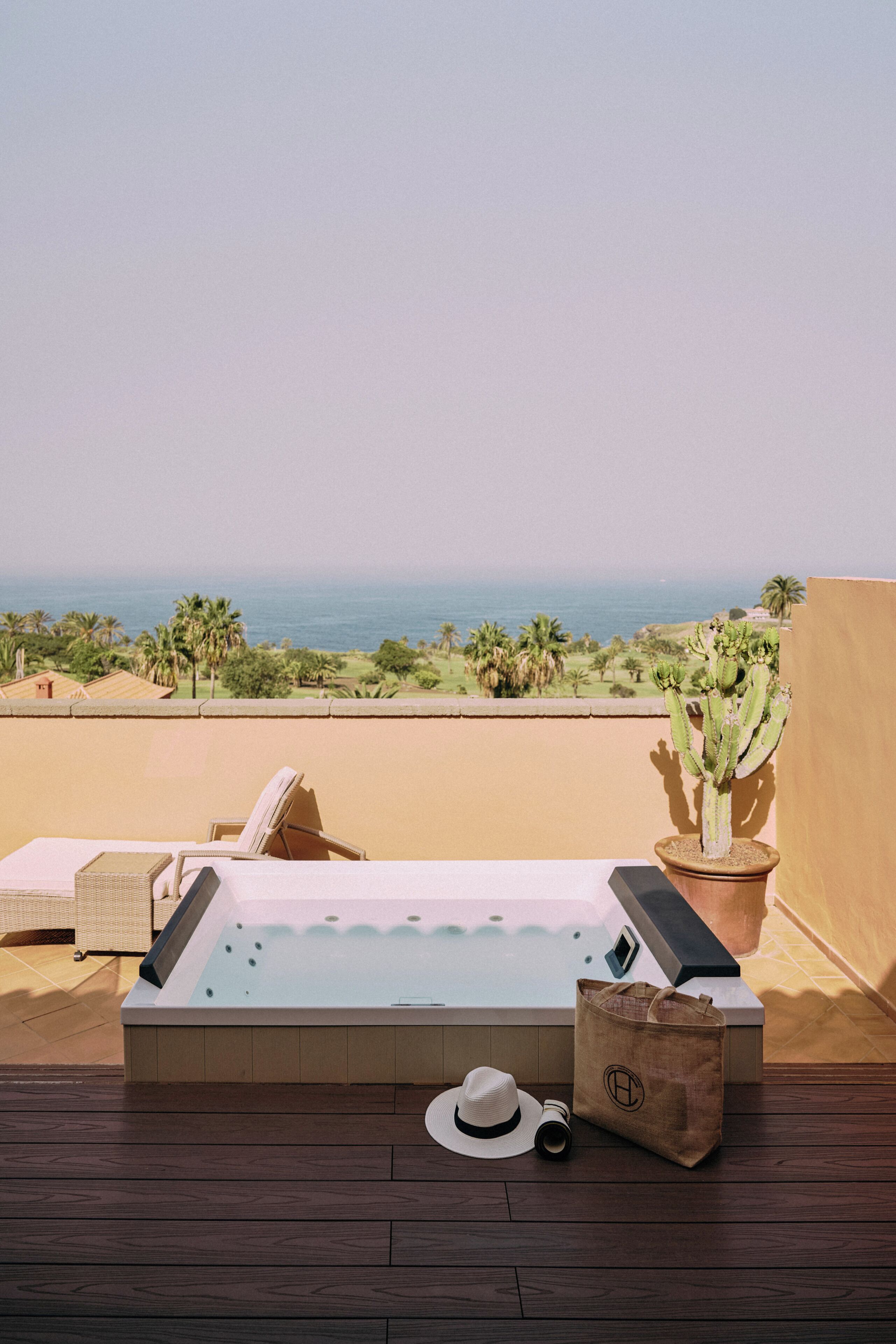 A spa area with a hot tub, a cactus, and a view of the ocean.