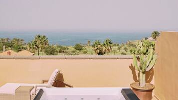 A spa area with a hot tub, a cactus, and a view of the ocean.