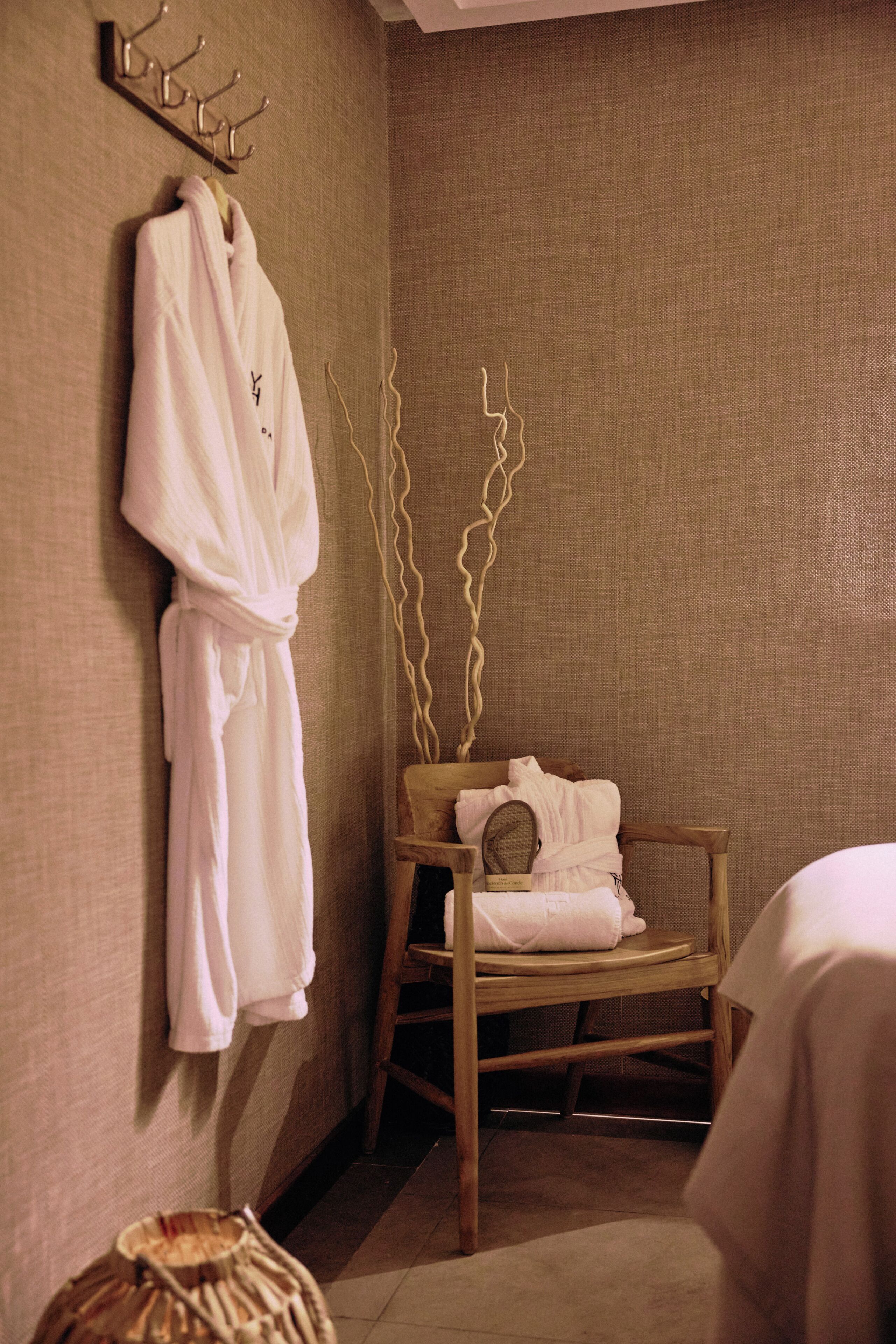 Una habitación con una silla de madera, una bata colgada y una toalla sobre la silla.