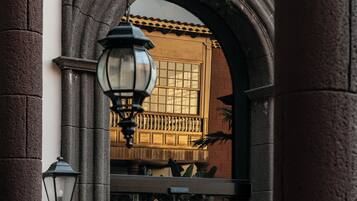 A stone archway with a lantern and a window with a view of a building.