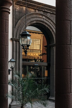 A stone archway with a lantern and a window with a view of a building. - Hotel Hacienda del Conde Meliá Collection Golf & Spa – Adults Only (Buenavista del Norte)