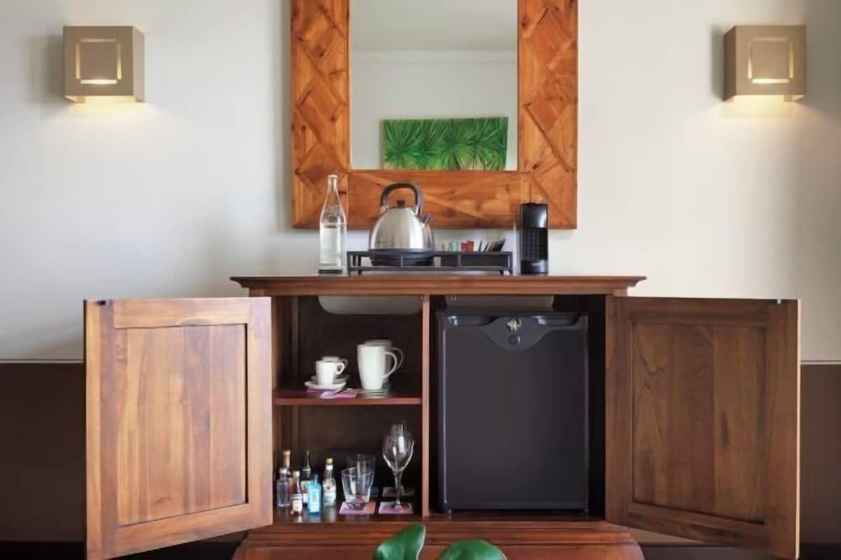 A compact kitchenette with a coffee maker, kettle, and storage cabinets.