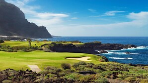 A coastal golf course with a clear view of the ocean and a mountainous backdrop. - Hotel Hacienda del Conde Meliá Collection Golf & Spa – Adults Only (Buenavista del Norte)