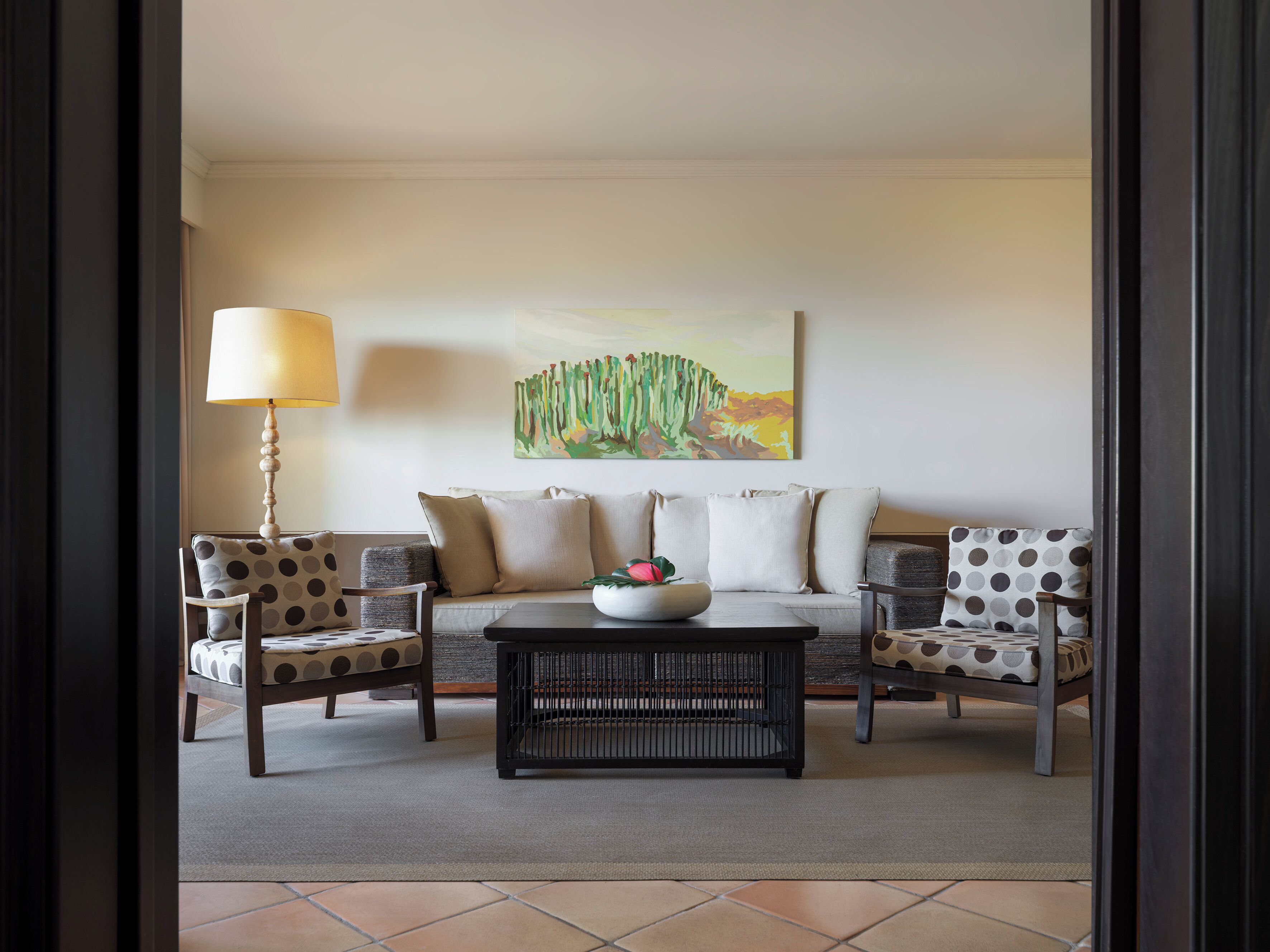 Een woonkamer met een bank, twee fauteuils, een salontafel en een lamp.