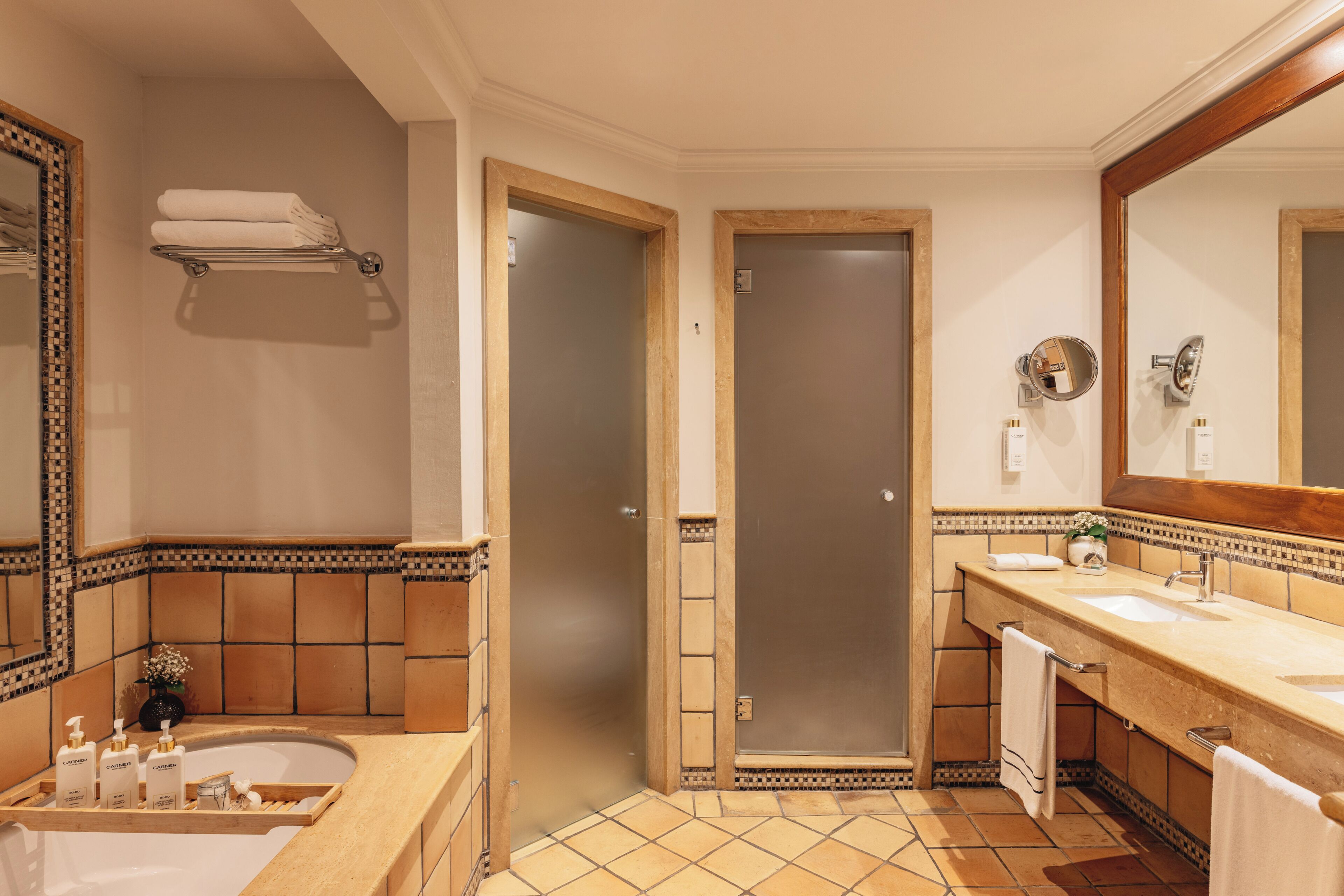Een badkamer met een bad, wastafel, spiegel en handdoekhouder.