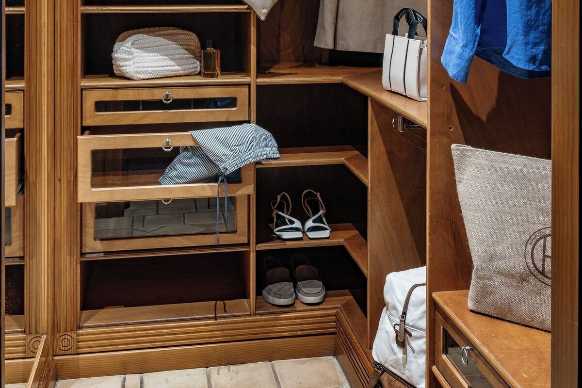 A wooden closet with shelves, a mannequin, folded clothes, and shoes.