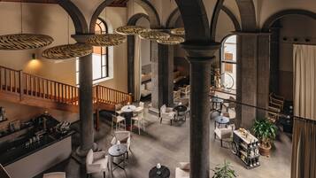 Un interior con techos altos, columnas arqueadas y una zona de bar central con asientos.