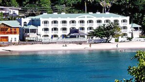 Un hôtel situé sur la côte, doté d’un grand bâtiment, d’une plage et d’une piscine.