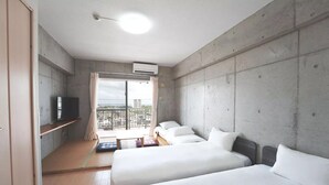 Una habitación de hotel moderna con dos camas, televisión y un balcón con vistas.