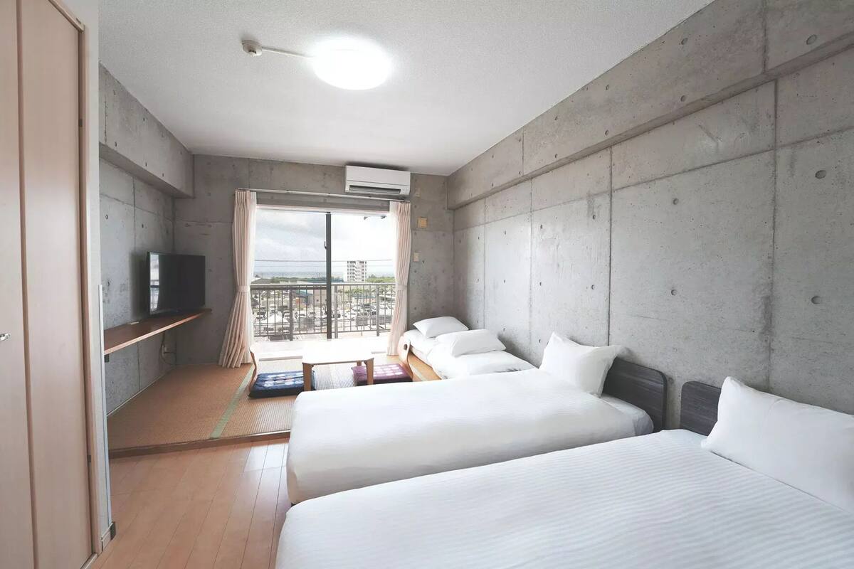 Une chambre d’hôtel moderne avec deux lits, une télévision et un balcon offrant une vue agréable.