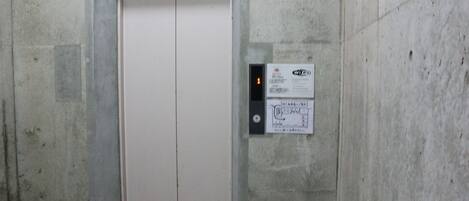 Puerta de ascensor sencilla con pantalla digital y un cartel en la pared.