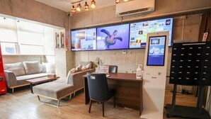 Habitación de hotel moderna con piso de madera, sofá, escritorio y un televisor de pantalla plana grande montado en la pared.