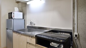 Una cocina compacta con un lavamanos de acero inoxidable, un microondas y un horno empotrado.