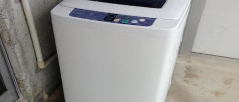 A white, compact, wall-mounted washing machine with a control panel featuring multiple buttons and a display screen.