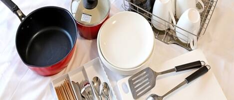 A kitchen area with various utensils, cookware, and dishes.