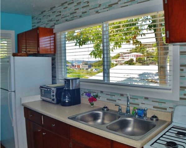 A kitchen with a double sink, a coffee maker, and a refrigerator.