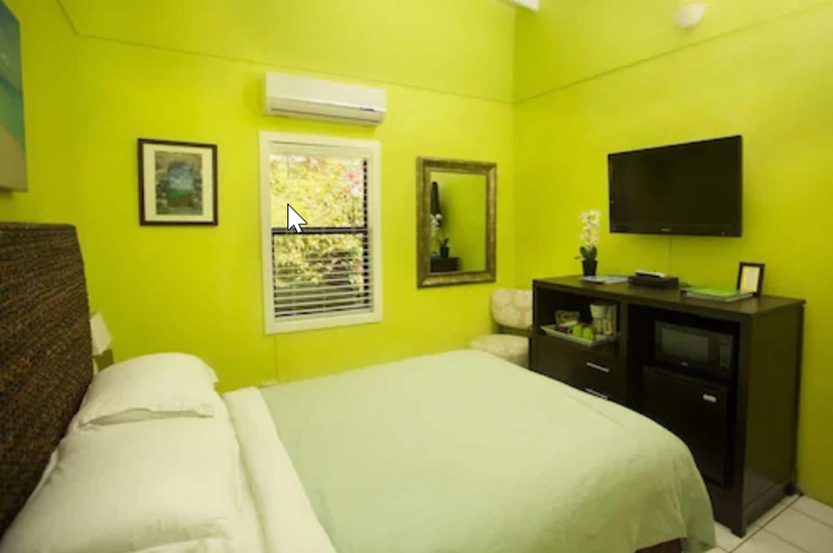 A room with a bed, a TV, a dresser, and a window with blinds.