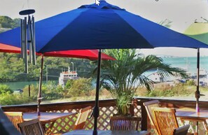 A deck with wooden chairs and a large blue umbrella.