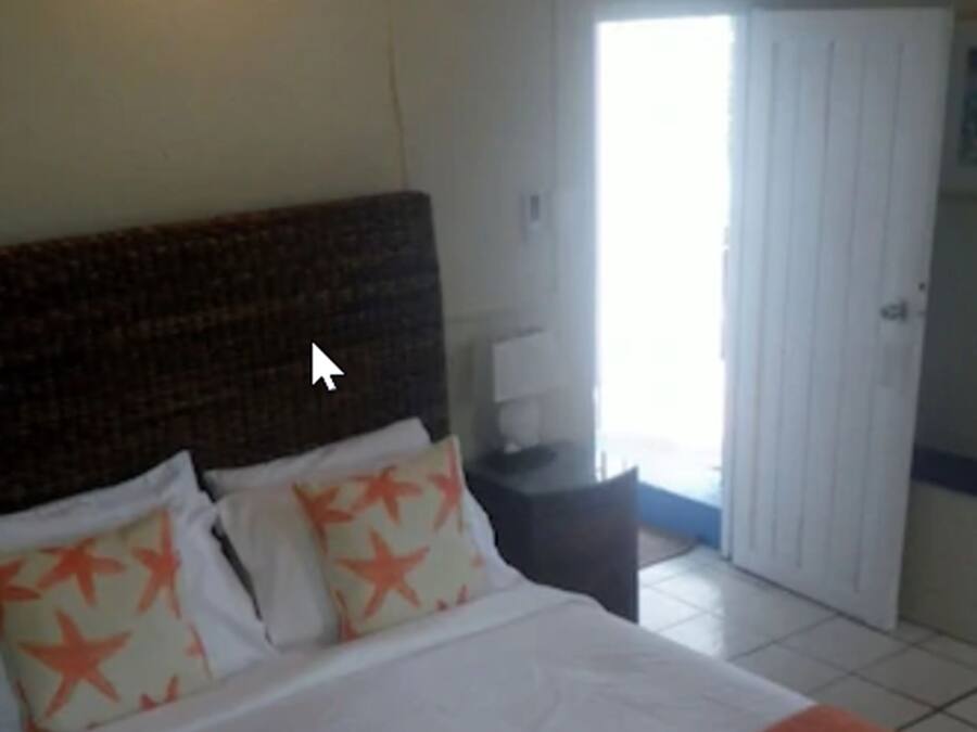Quarto de hotel com uma cama grande, uma mesa de cabeceira, uma luminária e uma porta que dá para uma varanda.
