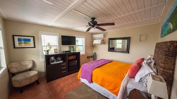 A bedroom with a bed, a ceiling fan, a dresser, a chair, and a window.