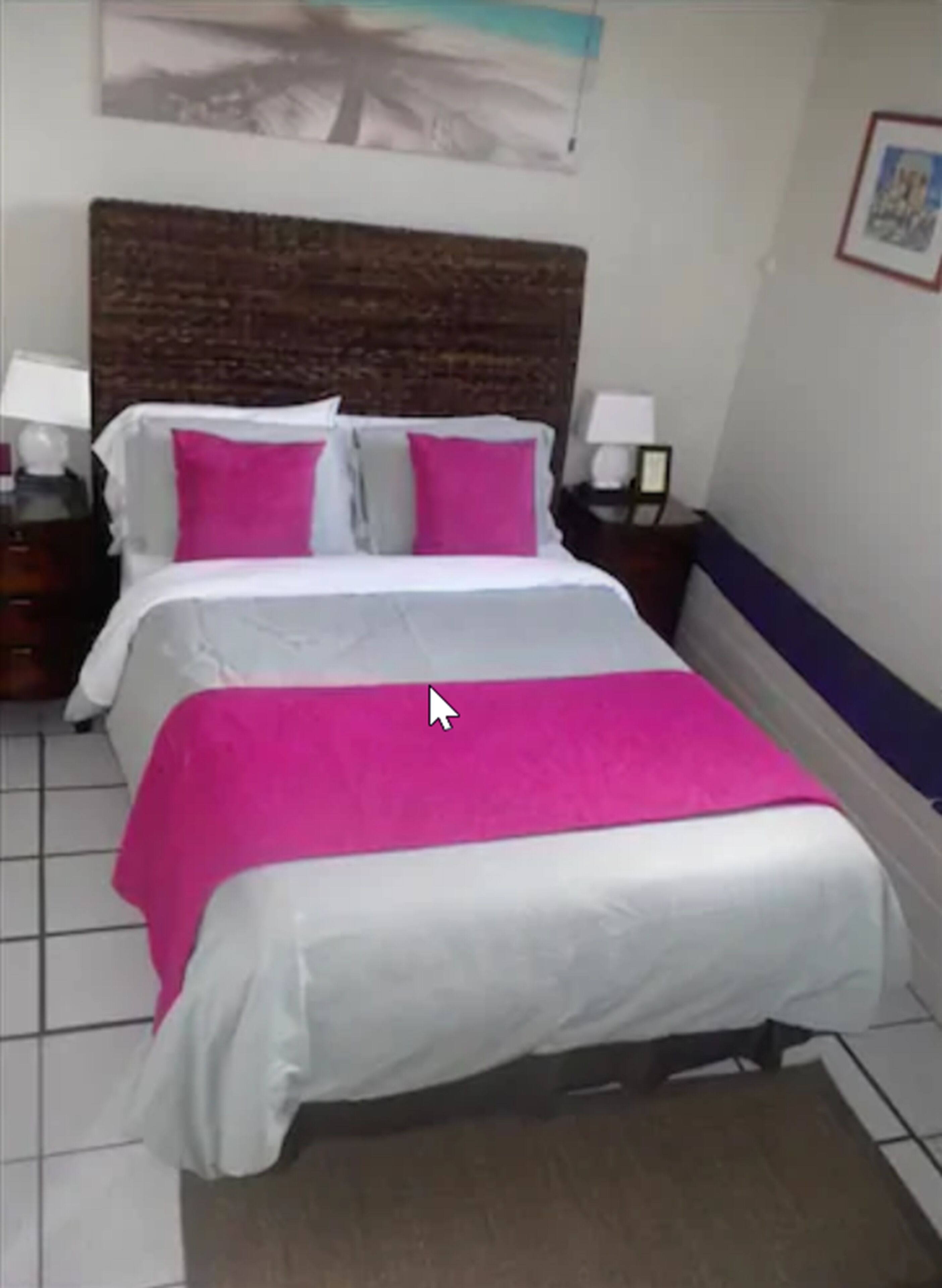 Una habitación de hotel con una cama, dos mesitas de noche y un cabecero.